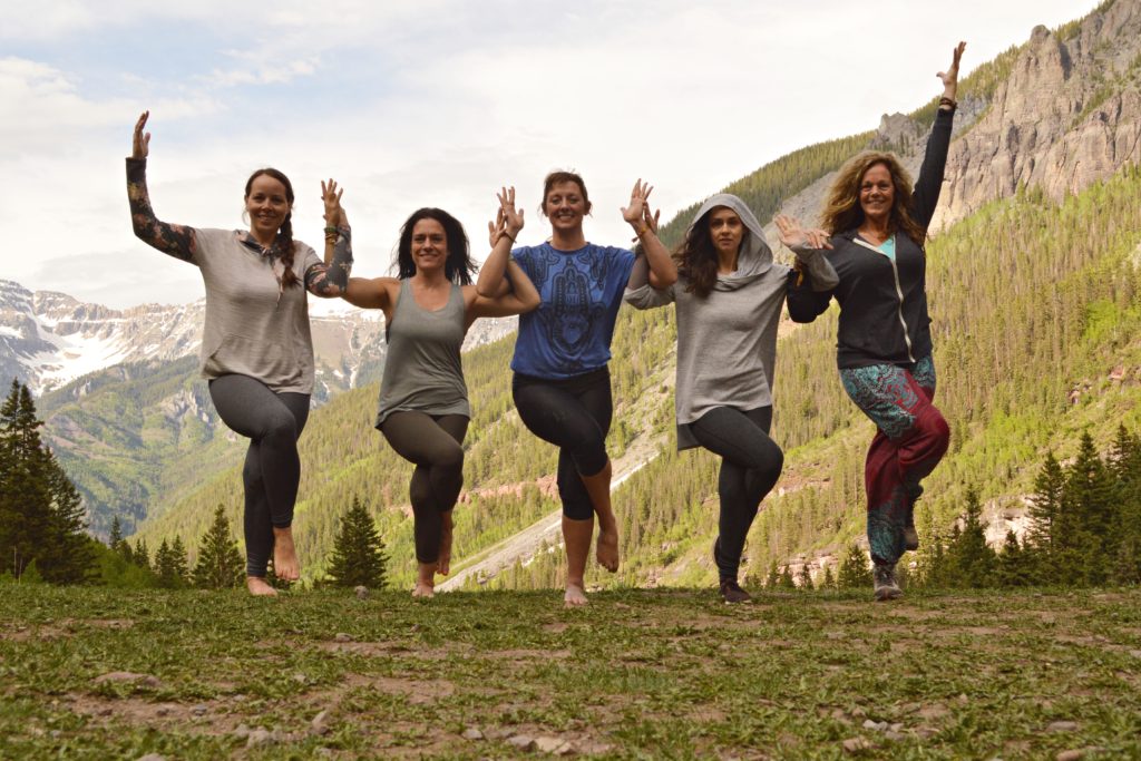 Christina and friends on a mountain connected in eagle pose