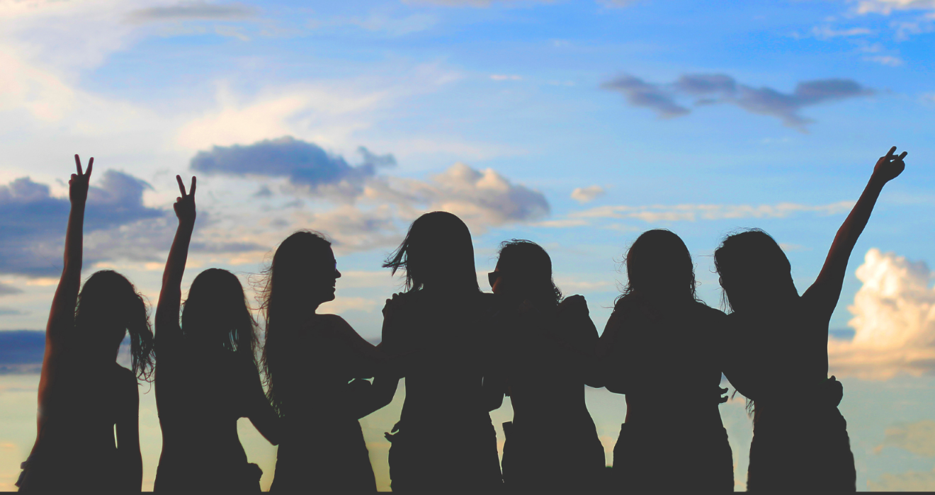 Silhouette of women together in wellness with a backdrop of blue sky with clouds