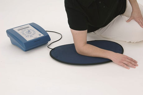Person leaning on a small PEMF mat for localized treatment