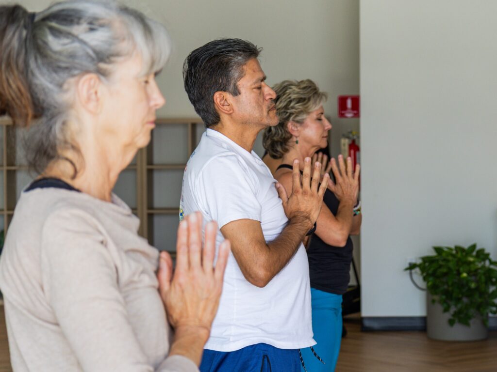 Side profile of students standing with hands in prayer position