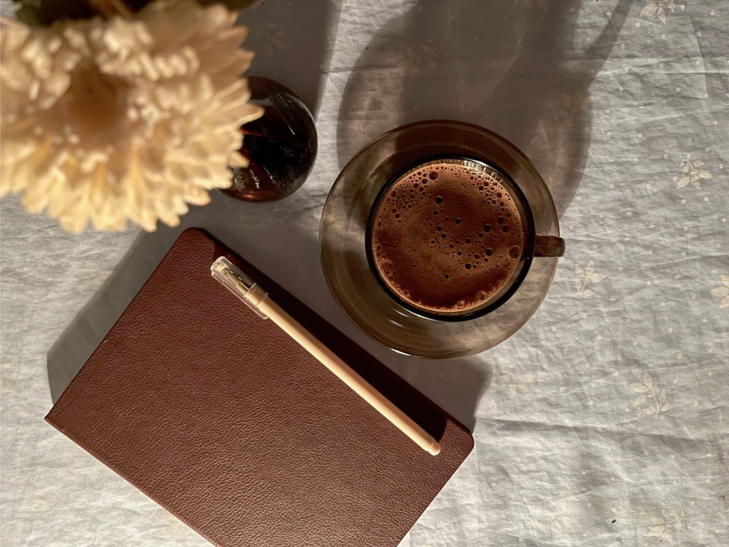 Journal with a cup of coffee and a pretty flower